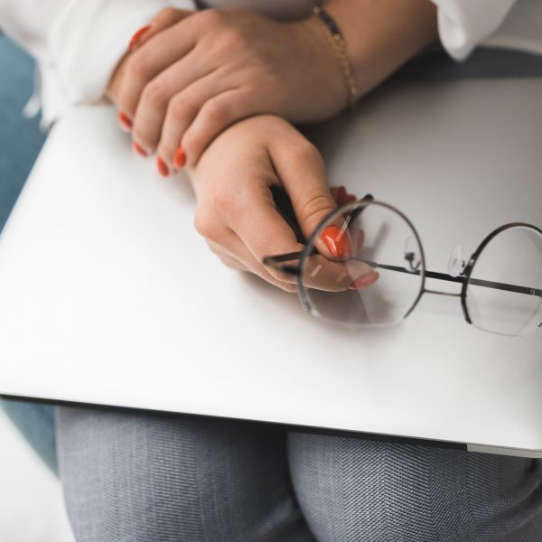 hands holding laptop and glasses